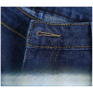 Detail showing precise orange contrast stitching and reinforced buttonhole on blue denim jeans