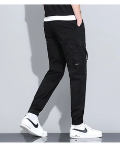 Detail of black cotton cargo pants showing large side pocket and ribbed jogger cuffs
