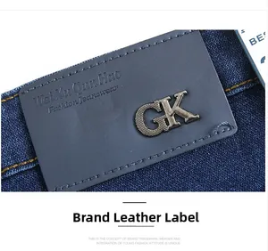 Detailed close-up of dark blue jeans waist with metal logo and leather brand patch