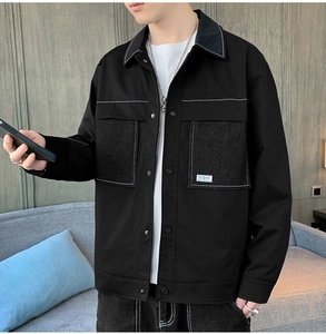 Detail of black workwear jacket with contrast stitching and denim patchwork pockets