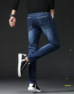 Detail view of men's slim fit dark blue jeans showing back pocket white contrast stitching
