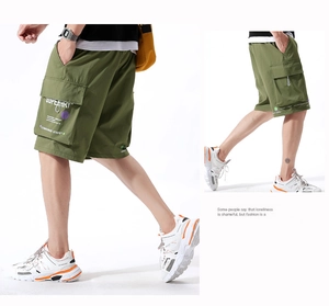 Detail of military green cargo shorts featuring large side pockets and letter printing