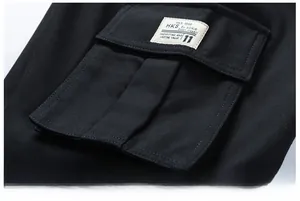 Close-up of black cargo pants side pocket with vintage woven label and cotton texture