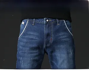 Detailed close-up of dark blue slim fit men's jeans featuring contrast stitching and metal button