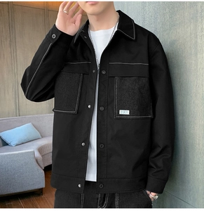 Detail of black casual jacket featuring white contrast stitching and double breast pockets