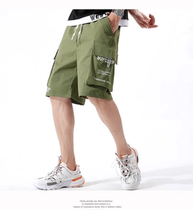 Close-up of olive green cargo shorts featuring white drawstrings and side flap pocket