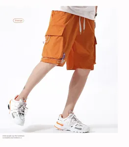 Detail of orange cargo shorts with large flap pocket and printed coordinate letters