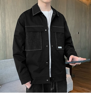 Detailed close-up of a black casual jacket showing contrast white stitching and metal buttons