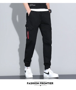Detail of men's black cargo joggers featuring a red metal zipper and functional side pocket