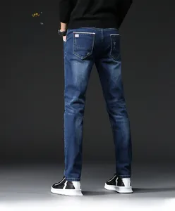 Detailed view of slim-fit denim jeans featuring whiskers and faded wash texture