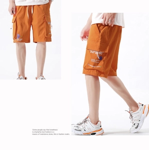 Close-up of bright orange cargo shorts featuring utility pockets and white drawstring waist