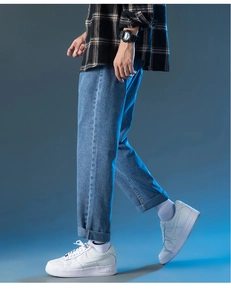 Detalle de vaqueros azules de pierna recta con dobladillo y zapatillas blancas