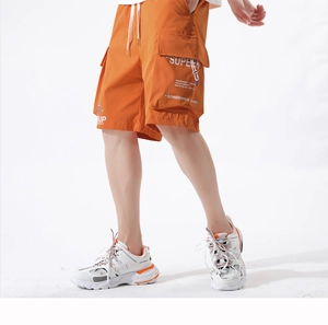 Detail of bright orange cargo shorts featuring utility pockets and Super text prints