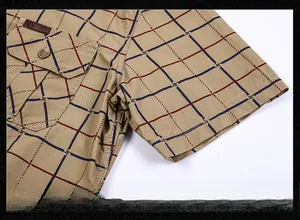 Detail of khaki plaid cotton shirt featuring functional chest pocket and outdoor leather label