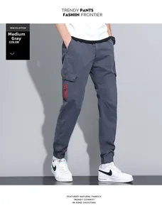 Detail of medium grey cargo pants featuring functional flap pockets and red zipper accents