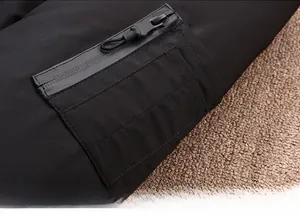 Detailed close-up of a decorative zipper pocket on the black puffer jacket sleeve