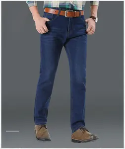 Close-up of men's dark blue straight-leg jeans with a brown leather belt and boots