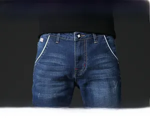 Detail view of men's blue slim fit jeans featuring cat-whisker wash and white piped pockets