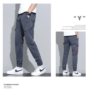 Detailed view of men's utility cargo pants with snap pocket and red side ribbon tag