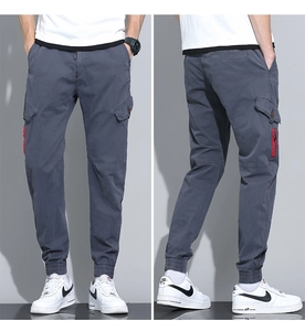 Detail of dark grey cargo pants featuring red zipper pocket and elastic ribbed cuffs
