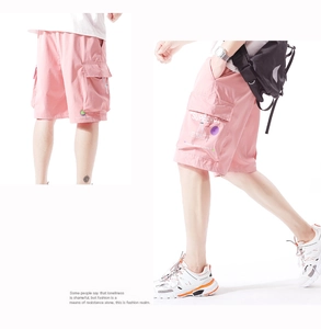 Detail of bright pink men's cargo shorts featuring large side pockets and graphic prints