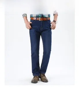 Detail of straight-leg dark blue jeans for men with brown leather belt and vintage shoes