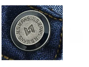 Close-up of vintage metal button with engraved logo on dark blue denim fabric