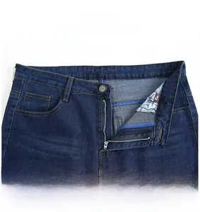 Detail shot of men's dark blue jeans featuring a metal button, zipper fly and denim texture