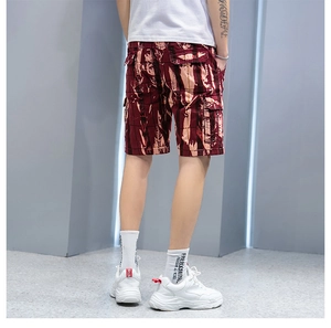 Detailed view of cargo shorts featuring a burgundy camouflage pattern and side flap pockets