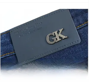 Detail of the waist area with grey leather brand patch and yellow stitching on navy jeans