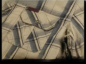 Detail of khaki plaid cotton shirt featuring a flap pocket and vintage metal button