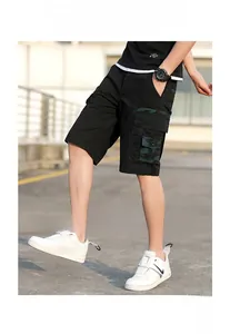 Detail view of cargo shorts with large camouflage utility pockets and black twill fabric