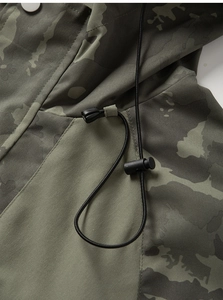 Detail of green camouflage hooded jacket with adjustable black drawstrings and toggles