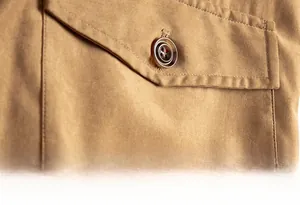Detail of khaki workwear jacket showing flap pocket texture and classic brown button