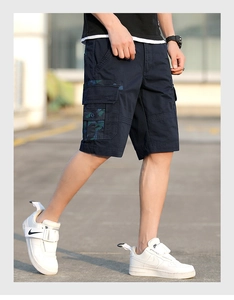Detailed side view of navy cargo shorts with green camouflage flap pocket and twill texture