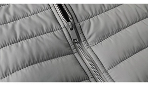Close-up of durable zipper and horizontal baffle quilting on gray winter jacket