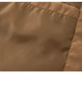 Detailed close-up of brown synthetic fabric with smooth texture and neat stitching details