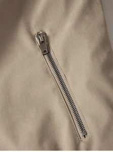 Nahaufnahme des robusten Silber-Metallreißverschlusses auf khakifarbenem Outdoor-Jackenstoff