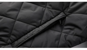 Detail of black quilted puffer jacket featuring diamond pattern and metal zipper pocket