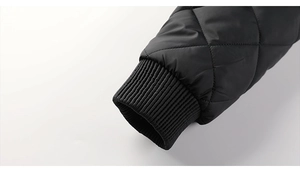 Detail of the black quilted jacket showing the ribbed cuff and diamond pattern stitching
