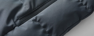 Close-up of the waterproof zipper and quilted fabric on a gray winter padded jacket