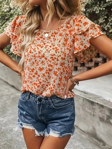 Détail de la blouse fleurie en mousseline à volants et du short en jean effiloché