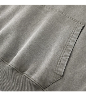 Detail of heavy washed cotton hoodie showing kangaroo pocket stitching and ribbed hem texture