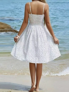 Detail of smocked elastic back and black polka dot pattern on a white summer beach dress