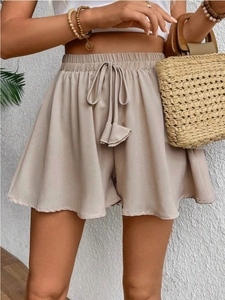 Dettaglio dei pantaloncini beige a vita alta con coulisse elastica e taglio a linea A