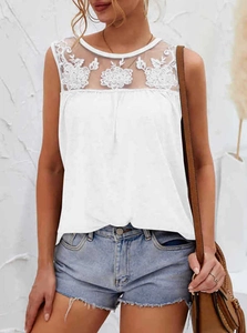 Dettaglio di un top bianco senza maniche con ricami in pizzo floreale e inserti in mesh velato