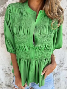 Detail of green summer shirt showing vertical pleats and matching front buttons on fabric