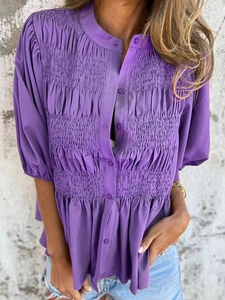 Detailed view of the purple smocked texture and button closure on this summer casual shirt