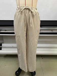 Detail of brown vertical striped wide leg pants with elastic drawstring waist and pockets