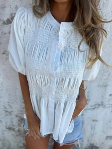 Detailed view of white smocked texture and buttoned front on summer short sleeve blouse